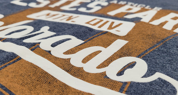 A screen print in cream and orange on a navy tee, close up